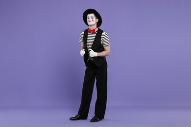 Photo of Funny mime artist in hat posing on purple background