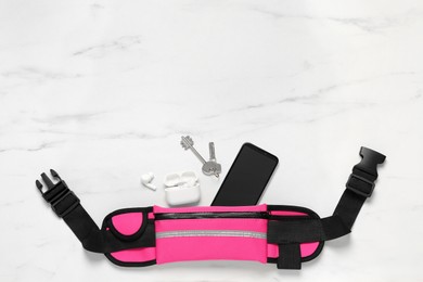 Flat lay composition with pink waist bag on white marble table, space for text
