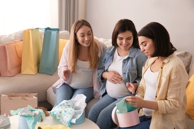 Photo of Happy pregnant women spending time together in living room after shopping