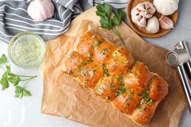 Photo of Buns of bread with garlic and herbs on grey table, flat lay