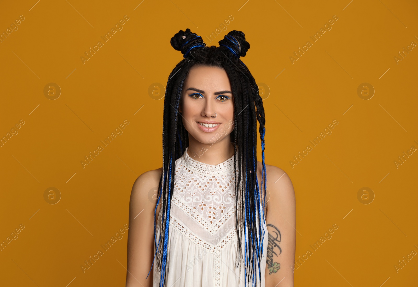 Photo of Beautiful young woman with nose piercing and dreadlocks on yellow background