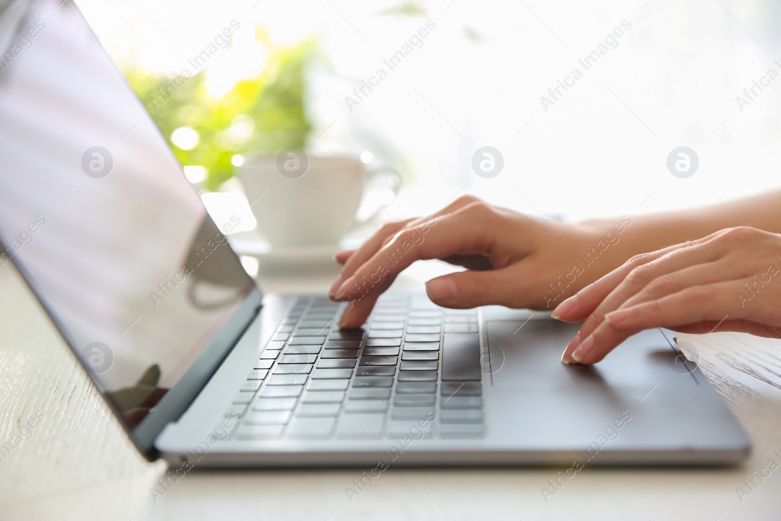 Photo of Woman working with modern laptop at white wooden table, closeup