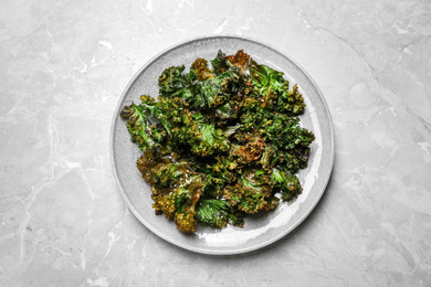 Tasty baked kale chips on light grey marble table, top view