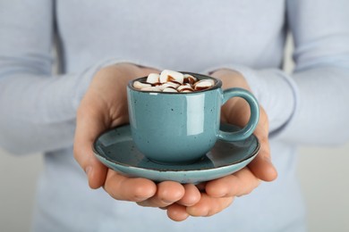 Photo of Woman holding cup of delicious hot chocolate with marshmallows and syrup, closeup