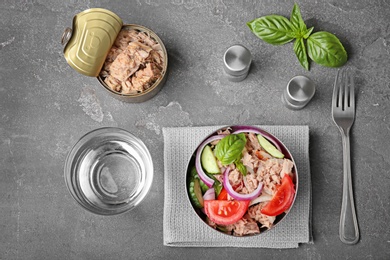 Flat lay composition with canned tuna and delicious salad on grey background