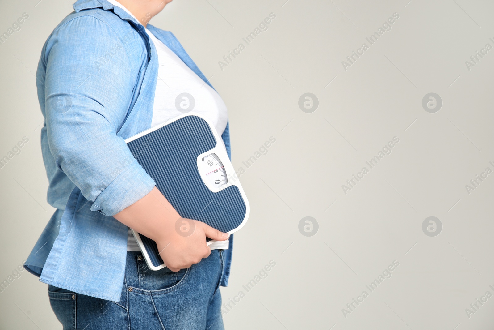 Photo of Overweight woman with scales on light background