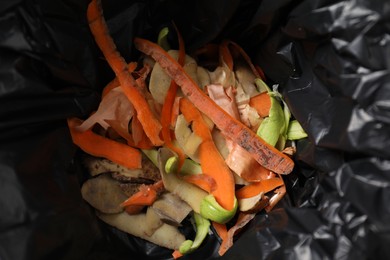Photo of Garbage bin with peels of fresh vegetables, above view