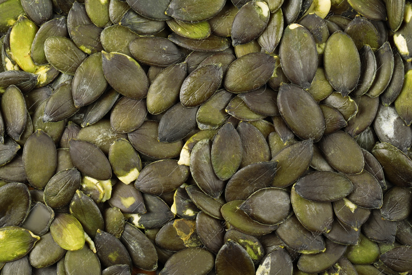 Photo of Many peeled pumpkin seeds as background, top view