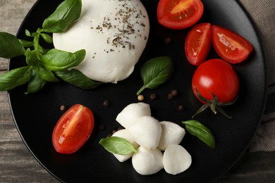 Delicious mozzarella with tomatoes and basil leaves on wooden table, top view