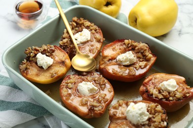 Photo of Tasty baked quinces with nuts and cream cheese in dish on table, closeup
