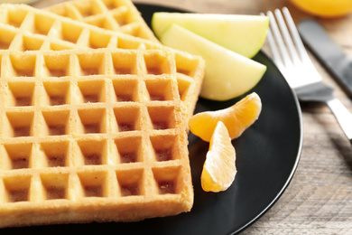 Photo of Waffles with fruits served on wooden table, closeup. Delicious breakfast