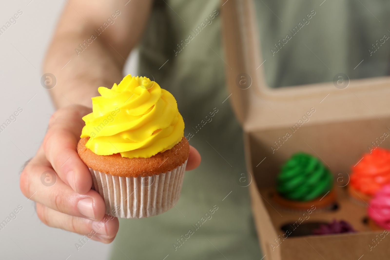 Photo of Man holding delicious cupcake with yellow cream, closeup. Space for text