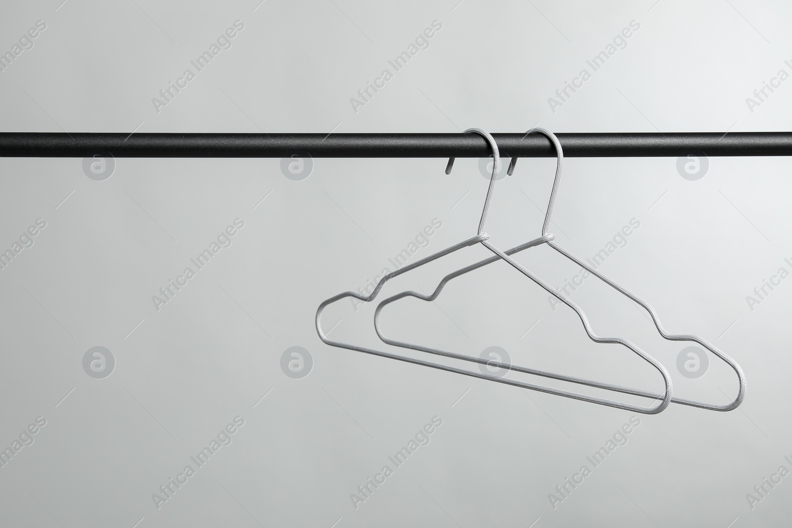 Photo of Empty clothes hangers on rack against grey background. Space for text