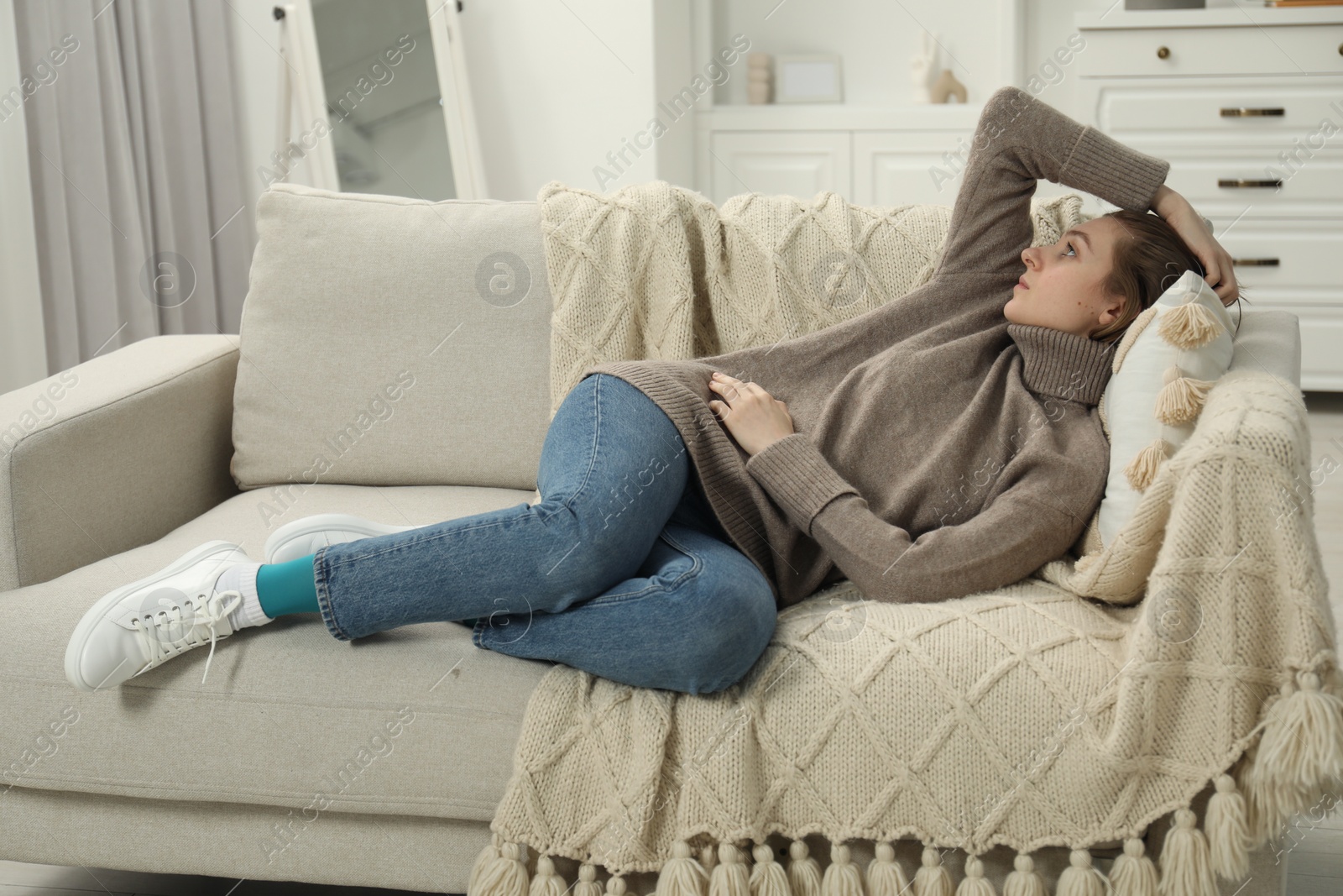 Photo of Sad young woman lying on sofa at home