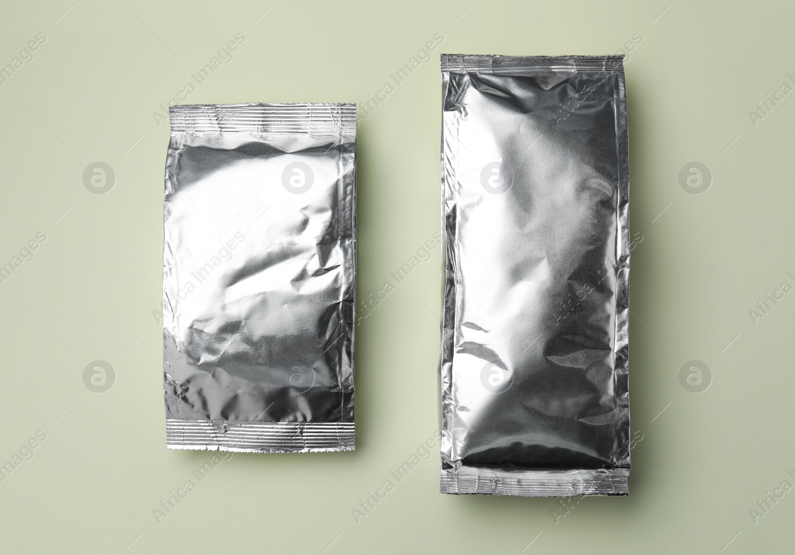 Photo of Blank foil packages on light background, flat lay