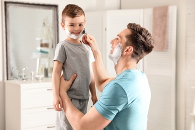 Dad pretending to shave his little son in bathroom