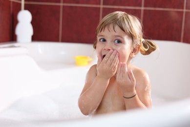 Photo of Little girl bathing in tub at home, space for text