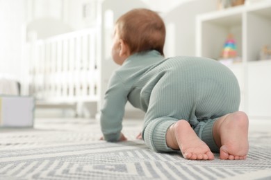 Photo of Cute baby crawling on floor at home, back view