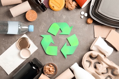 Photo of Recycling symbol and different garbage on gray background, top view