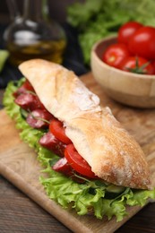 Delicious sandwich with sausages and vegetables on table, closeup