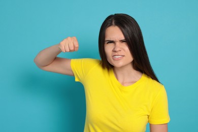 Young woman ready to fight on light blue background