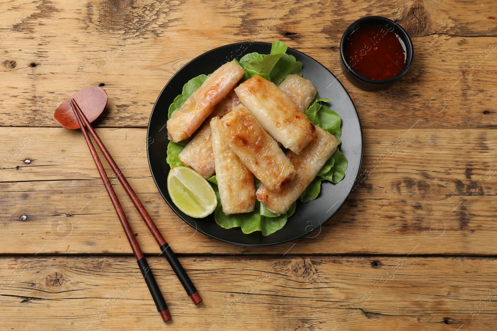 Photo of Tasty fried spring rolls served on wooden table, flat lay