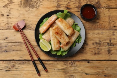 Photo of Tasty fried spring rolls served on wooden table, flat lay