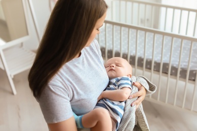 Mother with her sleeping baby near crib at home