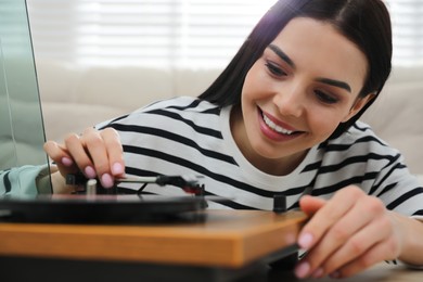 Photo of Happy young woman using turntable at home