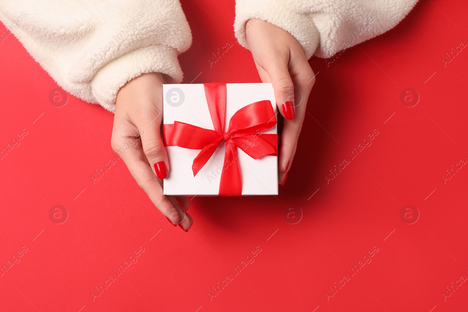 Photo of Christmas present. Woman with gift box on red background, top view