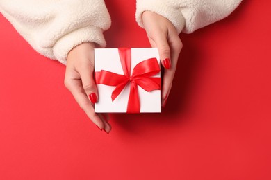 Photo of Christmas present. Woman with gift box on red background, top view