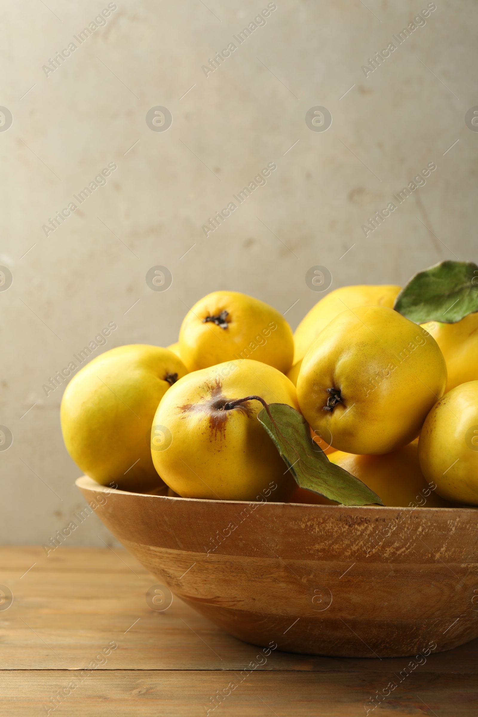 Photo of Tasty ripe quince fruits in bowl on wooden table, closeup