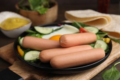 Photo of Delicious breakfast with boiled sausages and fried egg on wooden table, closeup