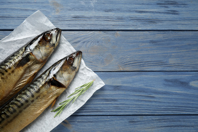 Photo of Tasty smoked fish on blue wooden table, top view. Space for text