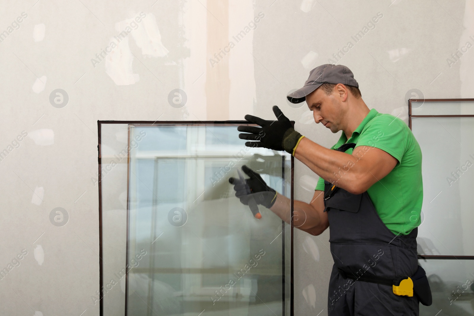 Photo of Worker in uniform preparing double glazing window for installation indoors