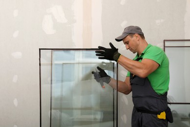 Worker in uniform preparing double glazing window for installation indoors