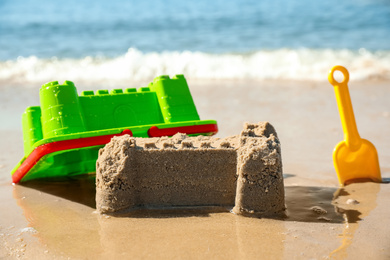 Photo of Child plastic toys near sand castle on beach