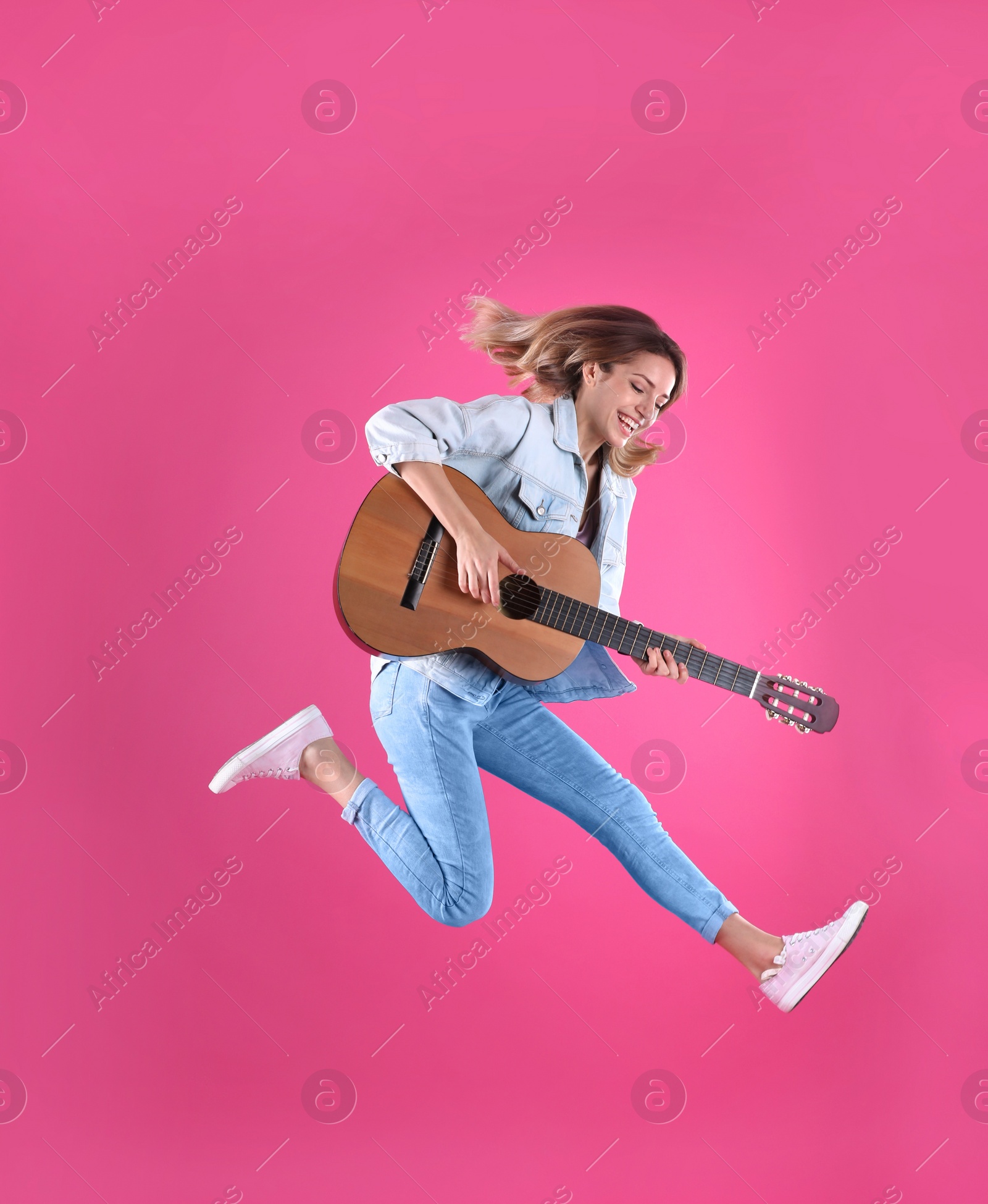 Photo of Young woman playing acoustic guitar on color background