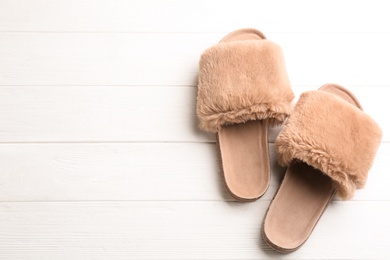 Photo of Pair of soft slippers on white wooden background, flat lay. Space for text