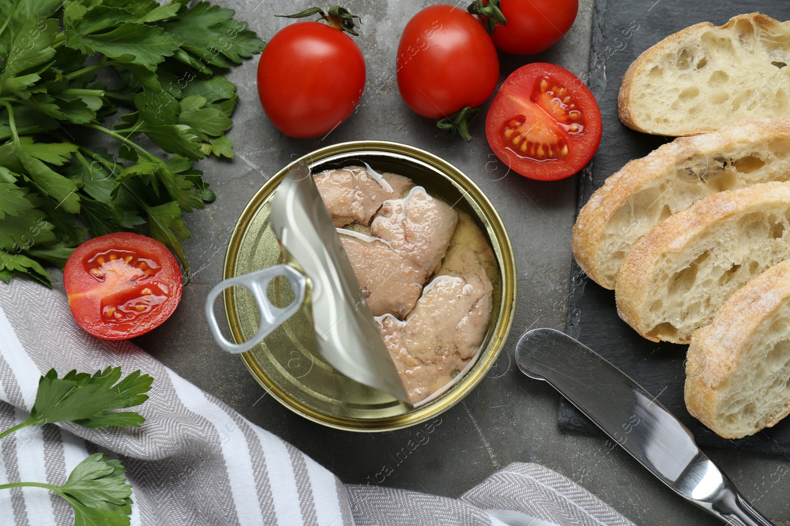 Photo of Flat lay composition with tin can of tasty cod liver and different products on grey table