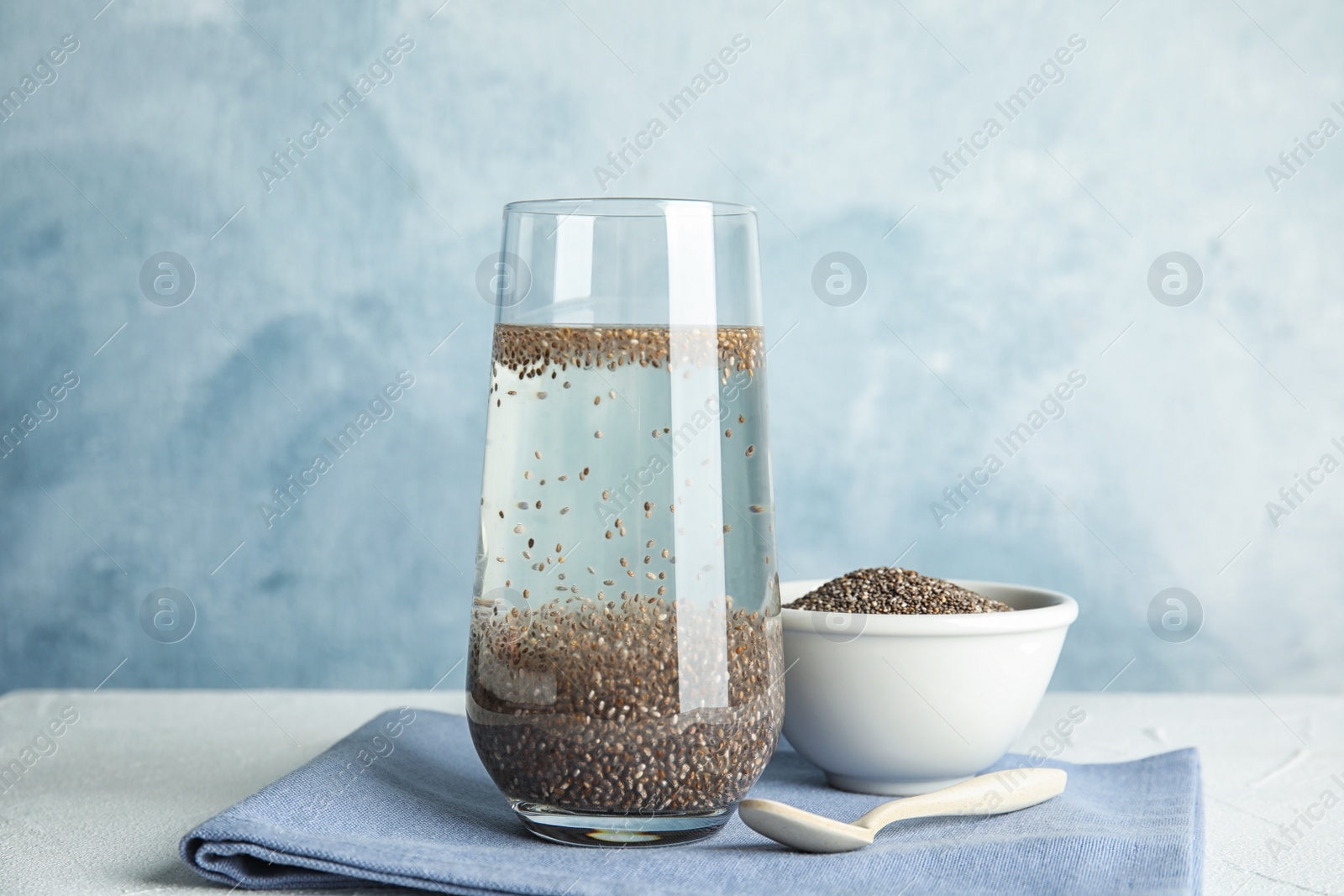 Photo of Composition with glass of water and chia seeds on table against color background