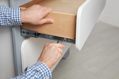 Photo of Man repairing chest of drawers in room, closeup
