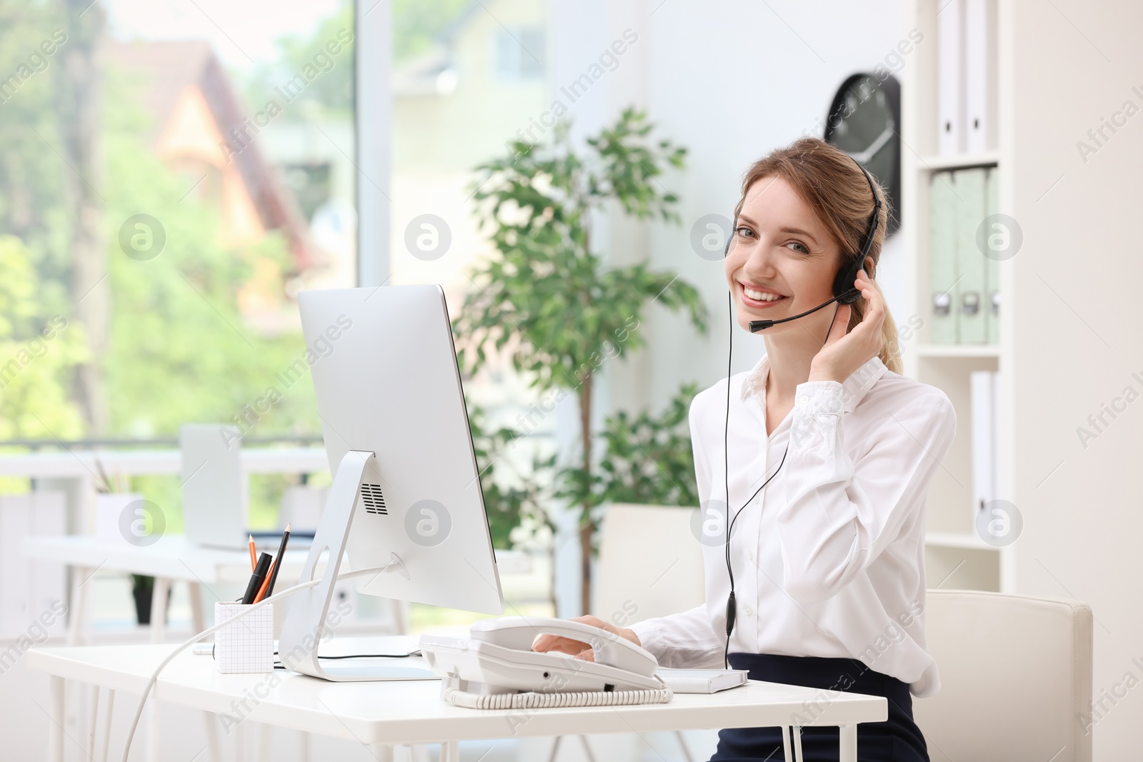 Photo of Female receptionist with headset at desk in office