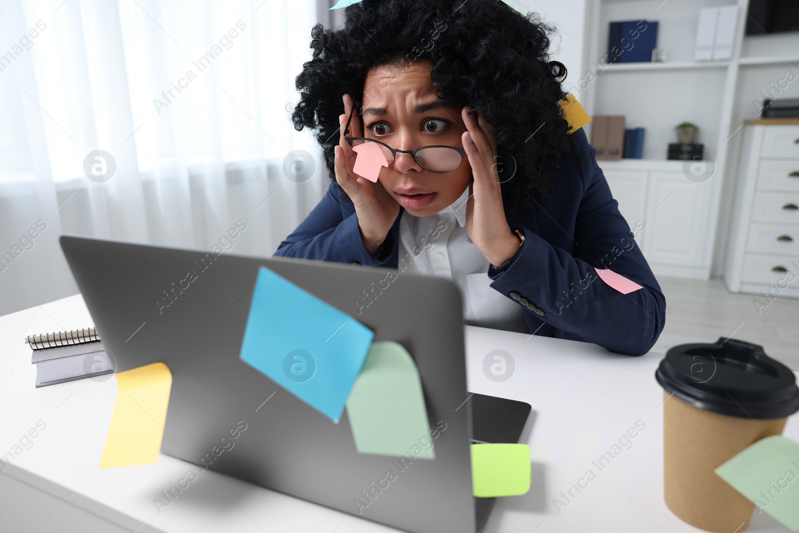 Photo of Deadline concept. Stressed woman looking at laptop in office. Many sticky notes everywhere as reminders