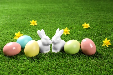 Ceramic Easter bunnies and dyed eggs on green grass