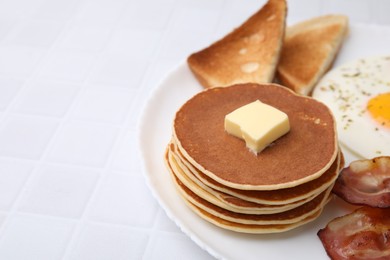 Photo of Tasty pancakes with fried egg and bacon on white tiled table. Space for text