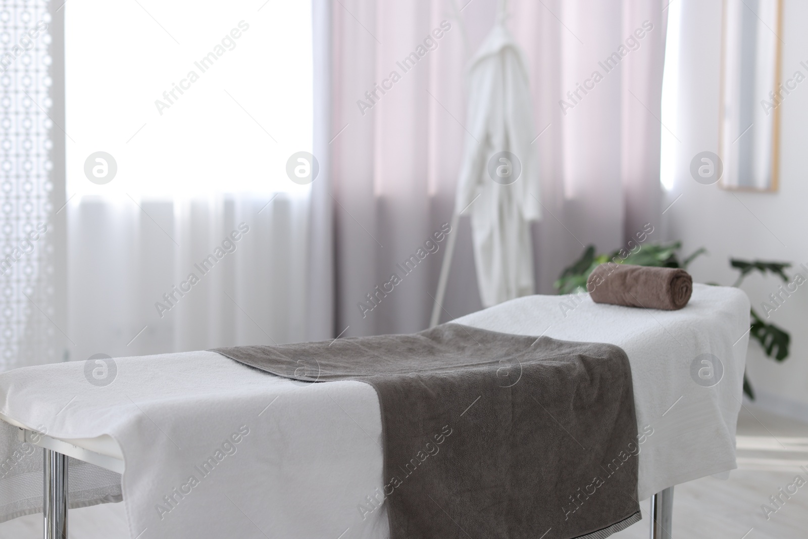 Photo of Comfortable massage table with clean towels in spa center