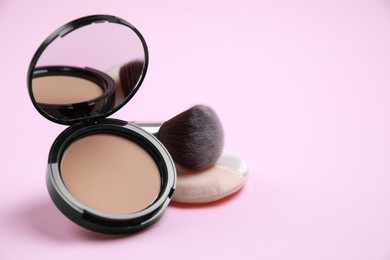 Photo of Face powder, brush and puff on pink background. Space for text