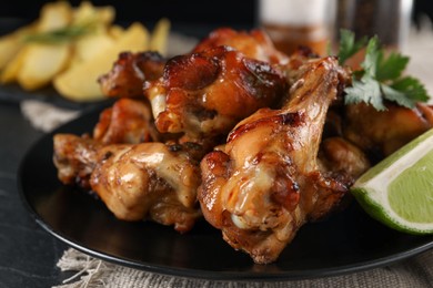 Delicious fried chicken wings on black plate, closeup