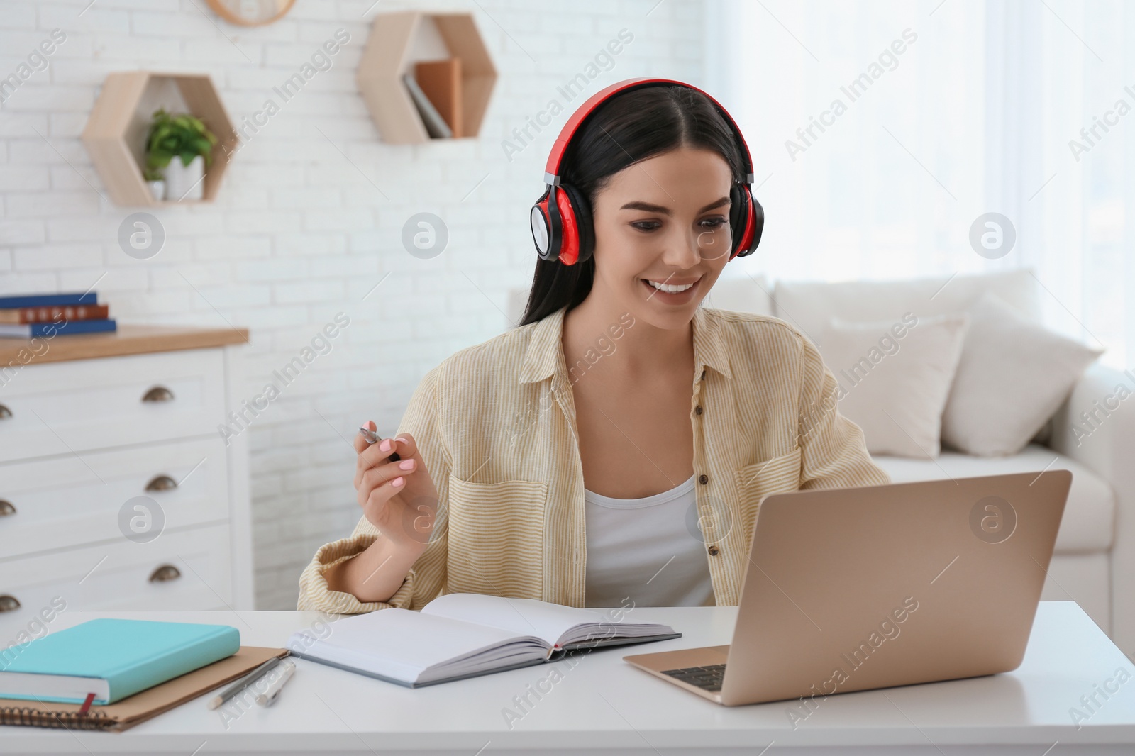 Photo of Young woman watching online webinar at table indoors